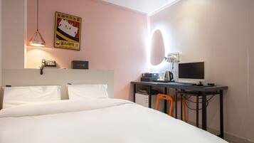 Ein Hotelzimmer mit Bett, Schreibtisch, Computer und einem Bild an der Wand.