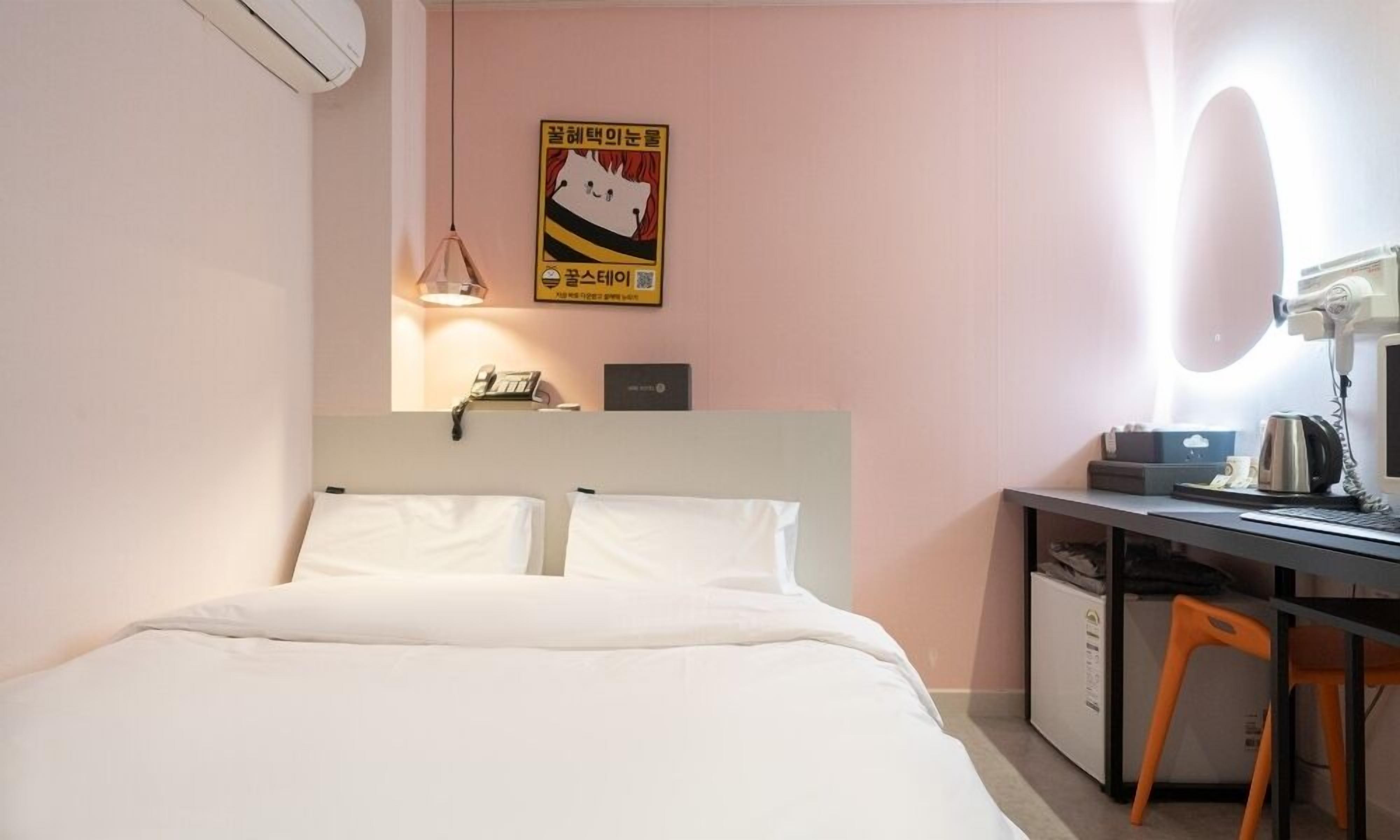Une chambre d’hôtel avec un lit, un bureau, une chaise et un miroir.