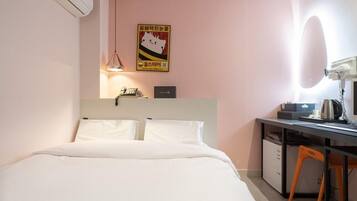Une chambre d’hôtel avec un lit, un bureau, une chaise et un miroir.