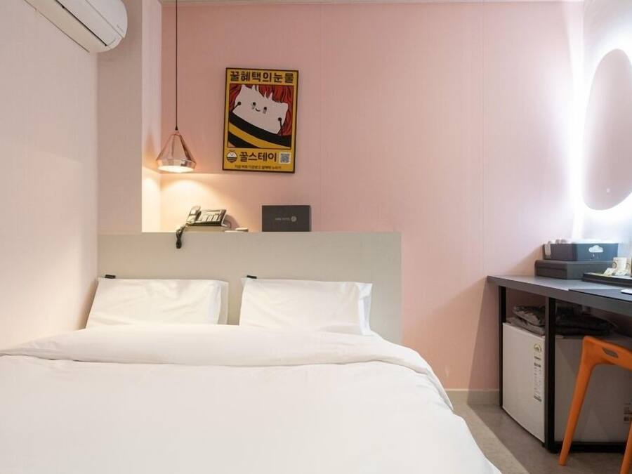 Une chambre d’hôtel avec un lit, un bureau, une chaise et un miroir.