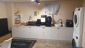 A compact kitchen with a coffee machine, a washing machine, and a sink. - Hotel Nine (Uiwang)