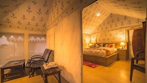 A tent-style room with a bed, bedside table, and a chair. - Osaka Desert Safari Camp (Jaisalmer)