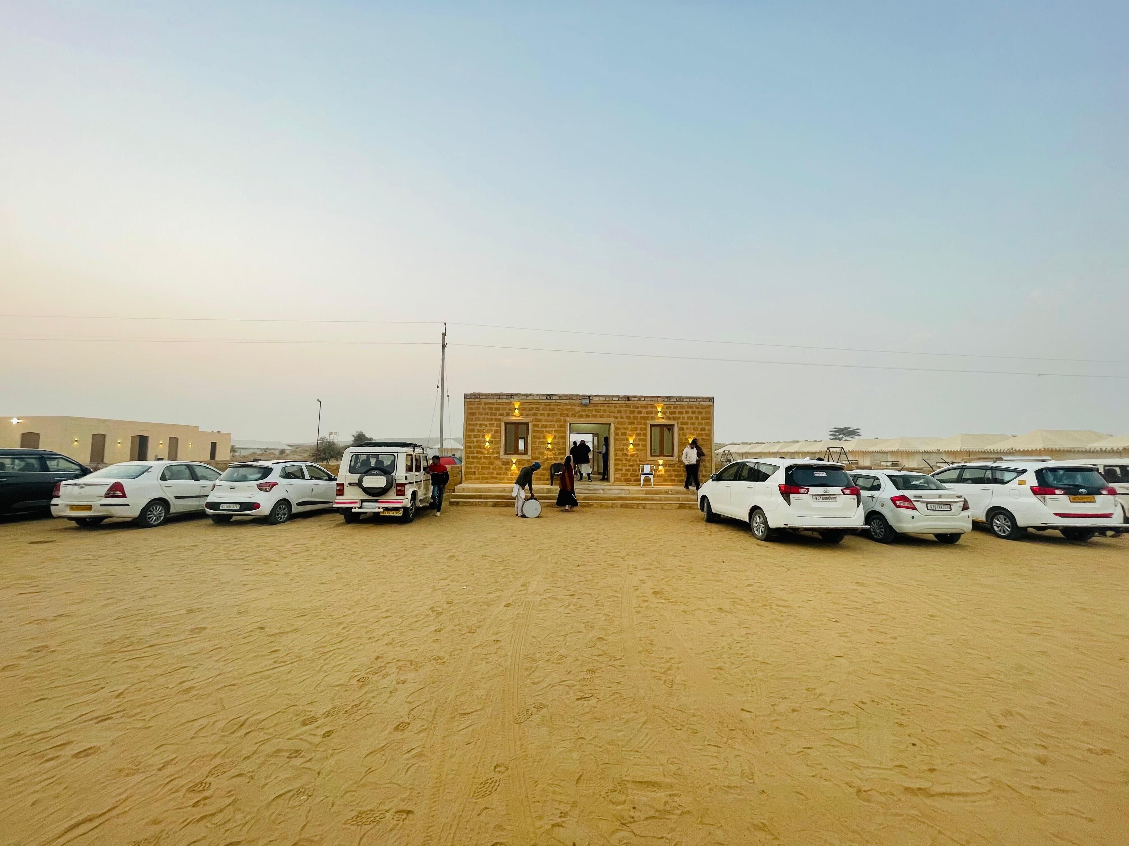 A parking area with several white cars and a small building with steps leading to the entrance.