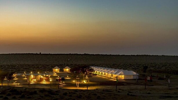 A series of tents with a row of lights in the foreground, suggesting a campsite or temporary accommodation area. - Osaka Desert Safari Camp (Jaisalmer)