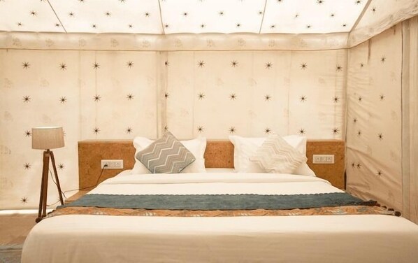 A neatly made bed with a patterned headboard, a bedside lamp, and a wall with star patterns.