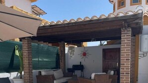 Une terrasse extérieure avec des meubles en osier, un barbecue et un élément décoratif sur le thème du soleil.