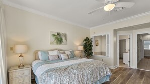 Ein Schlafzimmer mit einem großen Bett, zwei Nachttischen, einem Deckenventilator und einem Blumentopf.