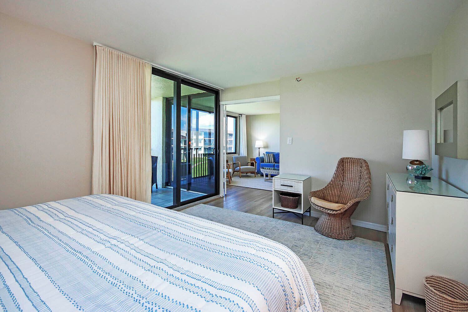 Ein Hotelzimmer mit einem großen Bett, einem Sessel, einem Schreibtisch und einer Glastür, die auf einen Balkon führt.