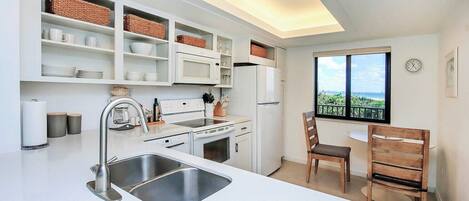 Una cocina moderna con armarios blancos, un lavamanos de acero inoxidable y una ventana con vistas.