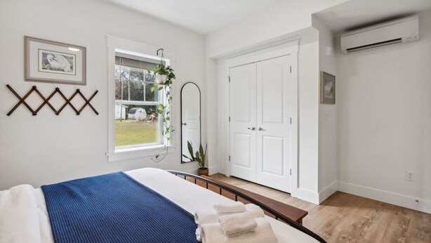 Een slaapkamer met een bed, een raam, een spiegel en een kledingkast.