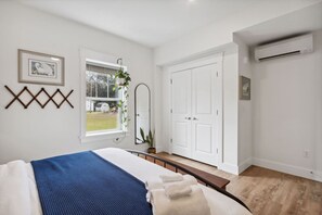 Un dormitorio con cama, ventana, espejo y armario.