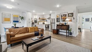 Een moderne woonkamer met een leren bank, een salontafel en een keuken op de achtergrond.