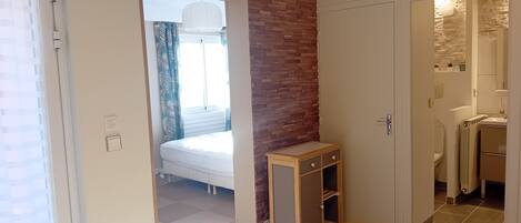 A room with a bed, a small desk, a bathroom, and a dining area with a table and chairs.