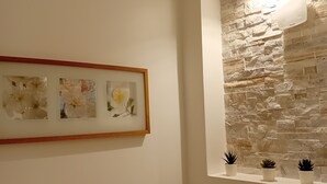 A bathroom with a stone wall, a framed picture, and three potted plants.