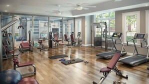 Un gimnasio moderno con cintas de correr, máquinas de pesas y colchonetas de ejercicio.