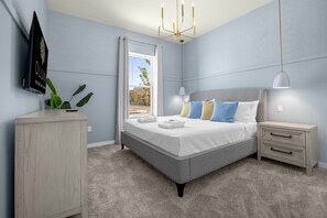 A modern bedroom with a bed, bedside tables, a wardrobe, and a TV on the wall.