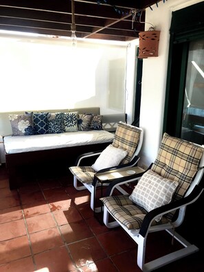 Relax in this inviting outdoor seating area with a bench and lounge chairs, surrounded by a wall with a window.