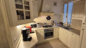 A compact kitchen with a gas stove, oven, microwave, and a coffee maker. - Borgo San Frediano Hideaway  (Florence)