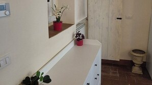 A bathroom with a white vanity, a mirror, a potted plant, and a white door. - Borgo San Frediano Hideaway  (Florence)