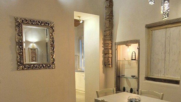 A dining area with a wooden table and chairs, a mirror on the wall, and a stone accent wall. - Borgo San Frediano Hideaway  (Florence)