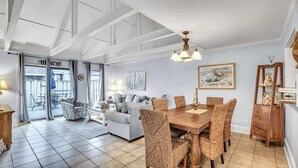A spacious living area with a dining table, wicker chairs, a sofa, and a painting on the wall. - Luxury Pet-Friendly Villa! Near Golf, Hilton Head (Hilton Head Island)