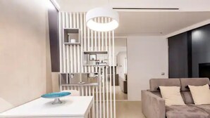 A modern living room with a white table, a grey sofa with cushions, and a white partition with vertical lines. - Charming stay in Rome: Luxury apartment one step from St. Peter's Basilica (Roma)