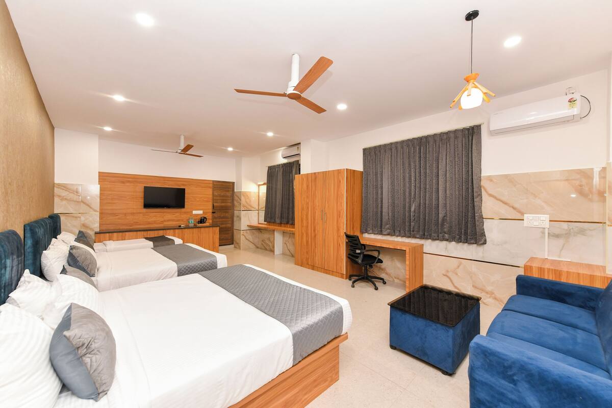 A modern hotel room with two beds, a desk, a chair, and a TV.