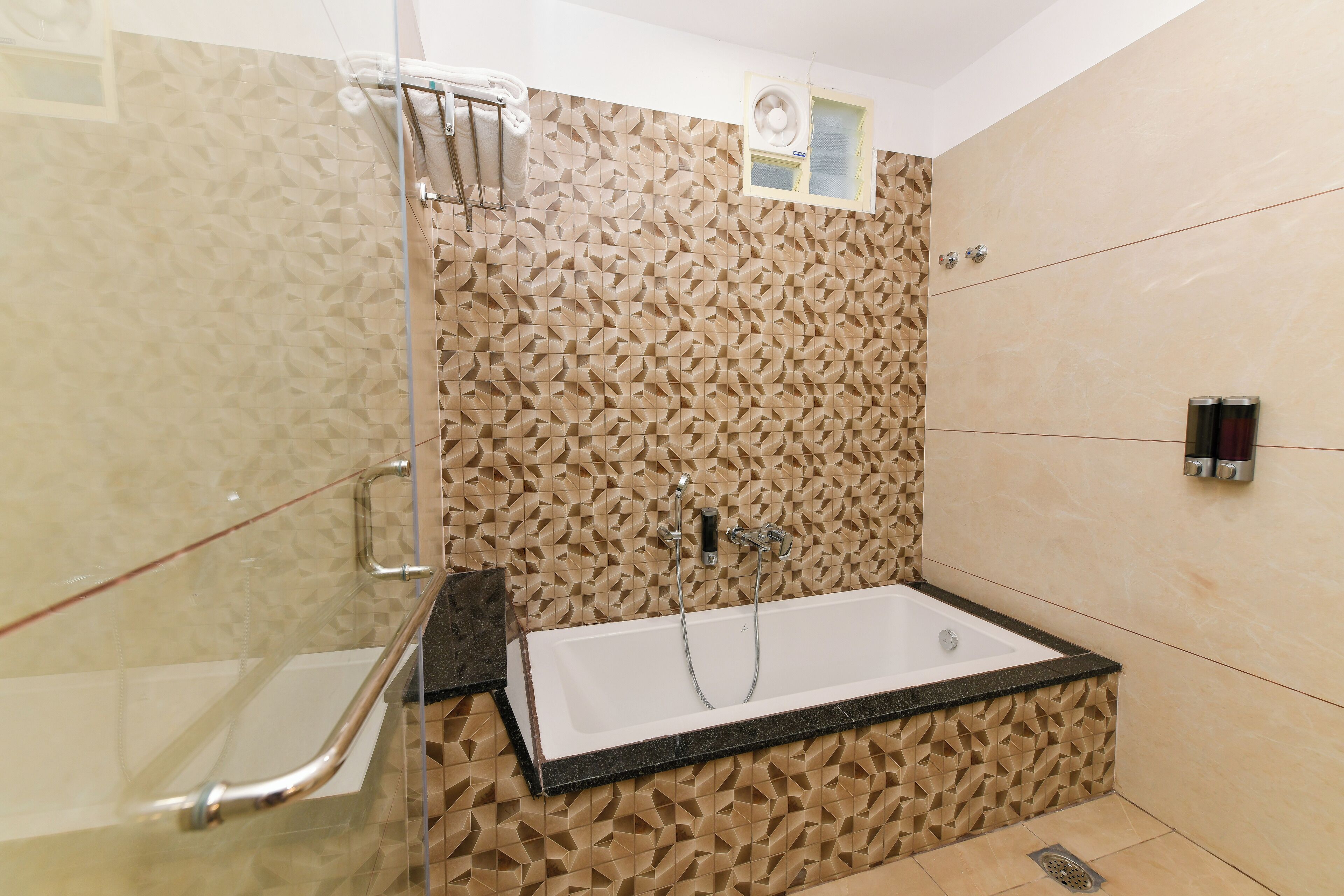 A modern bathroom with a freestanding bathtub, a glass shower enclosure, and a patterned wall.