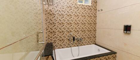 A modern bathroom with a freestanding bathtub, a glass shower enclosure, and a patterned wall.