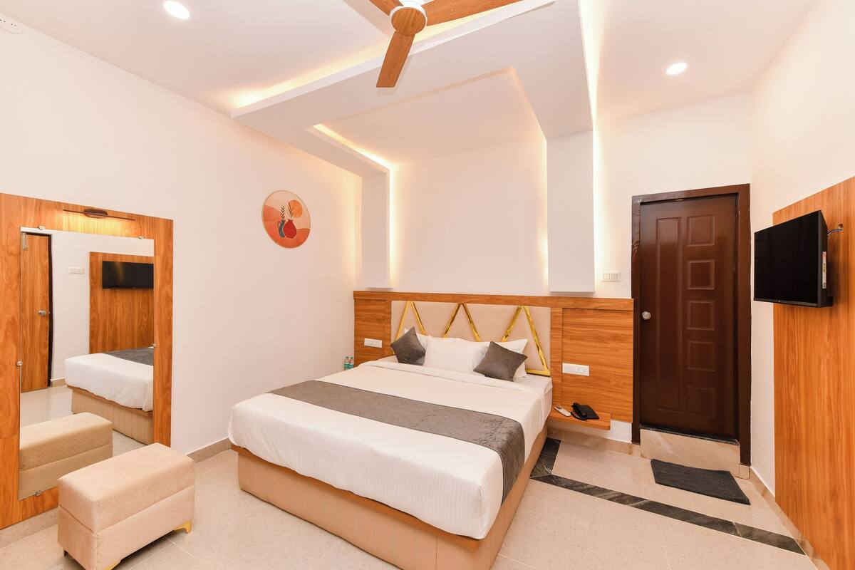 A modern bedroom with a large bed, bedside tables, a wardrobe, a mirror, and a ceiling fan.