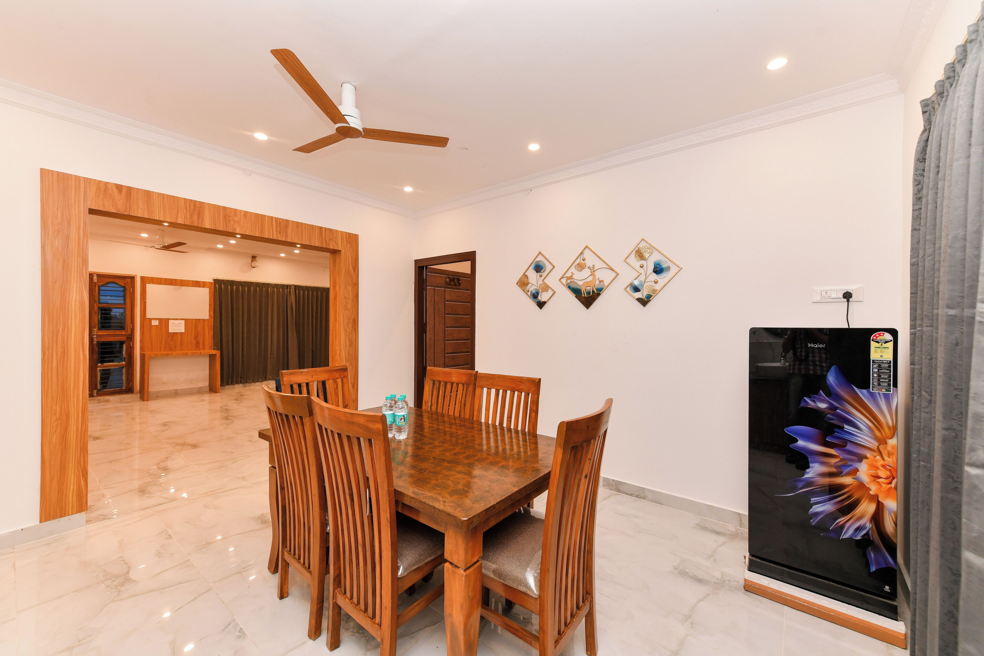 A dining area with a wooden table and chairs, a ceiling fan, and a refrigerator with a decorative sticker.