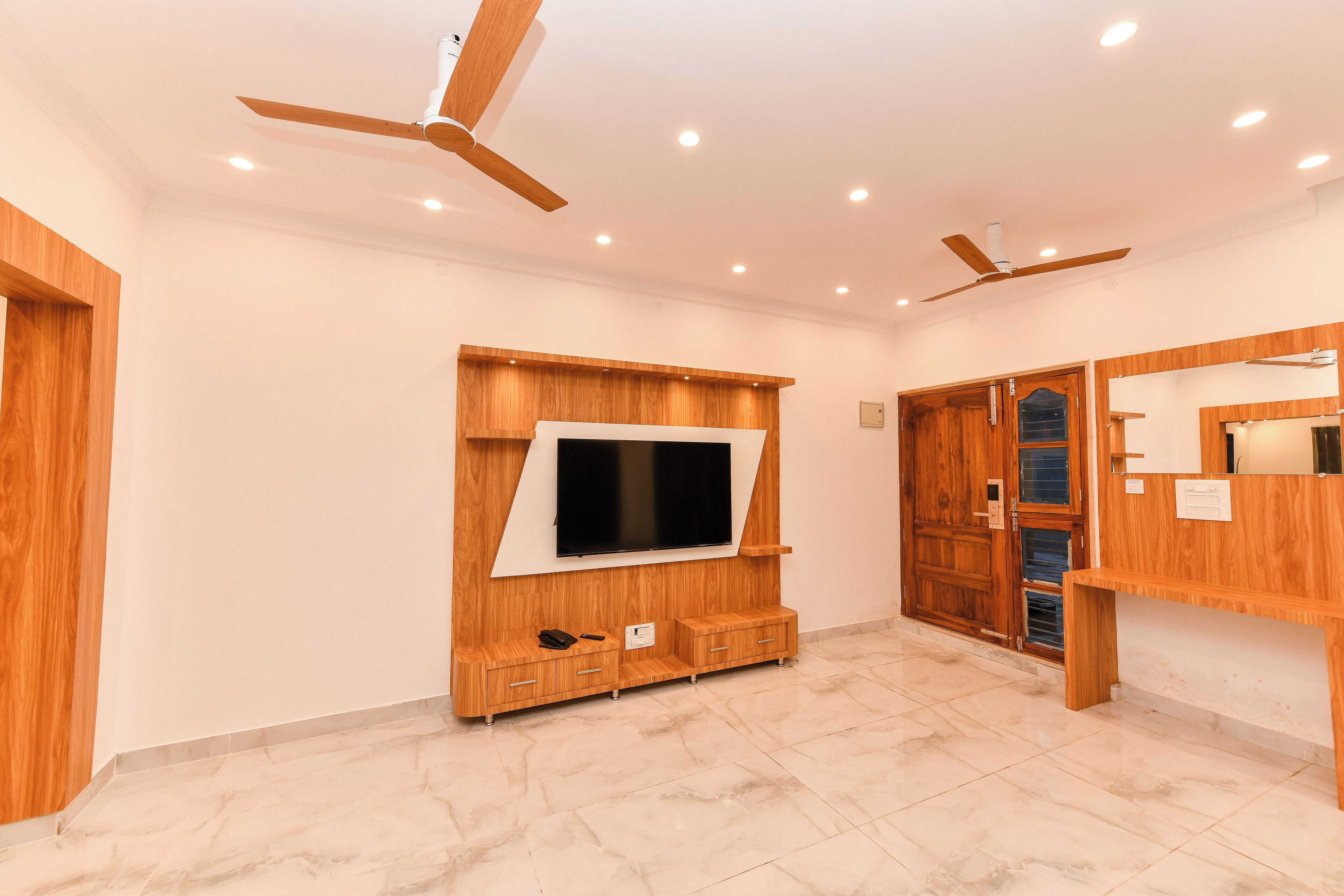 A modern bathroom with a wooden vanity, a built-in TV, and ceiling fans.