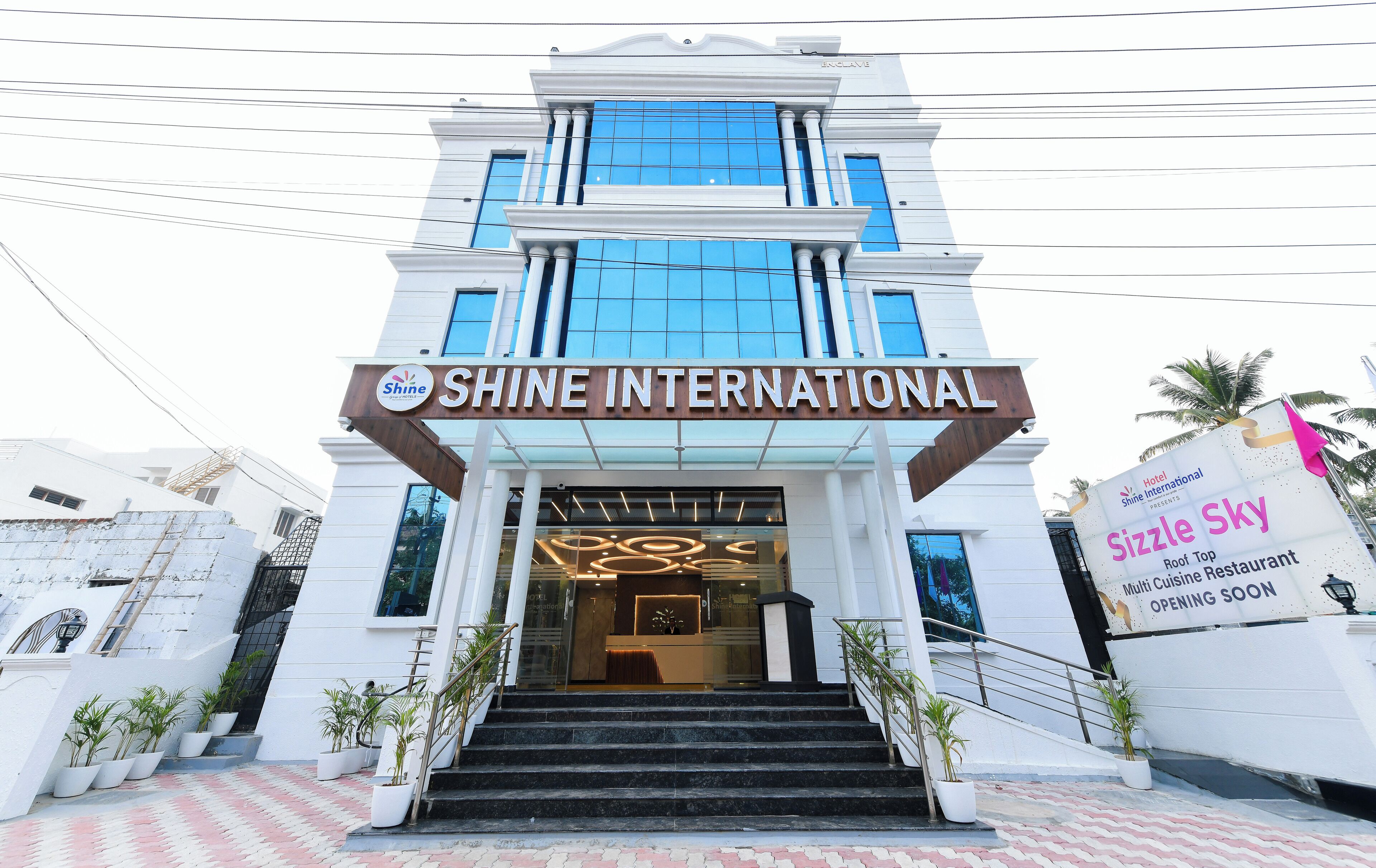 Der Eingang des Hotels Shine International mit modernem Design, gekennzeichnet durch eine auffällige Schilderung und eine Treppe zum Eingang.