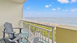 A balcony with Adirondack chairs, a pool, and a view of the beach and ocean. - Bay Watch 636- 1BR/1BA-Oceanfront-Lazy River (North Myrtle Beach)