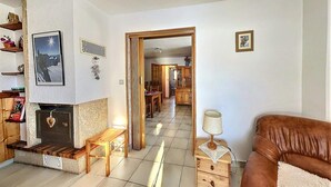 Una sala de estar con chimenea, un sofá, una mesa con lámpara y un pasillo que conduce a un comedor.