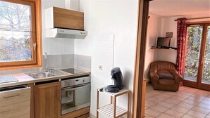Una cocina con armarios de madera, horno empotrado y una cafetera sobre una estante.