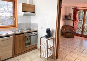 Eine Küche mit Holzausstattung, einem Einbauofen und einer Kaffeemaschine auf einem Regal.