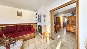 Una sala de estar acogedora con un sofá rojo, una mesita con una planta y una chimenea.
