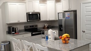 Una cocina moderna con armarios blancos, electrodomésticos de acero inoxidable y encimera de granito.