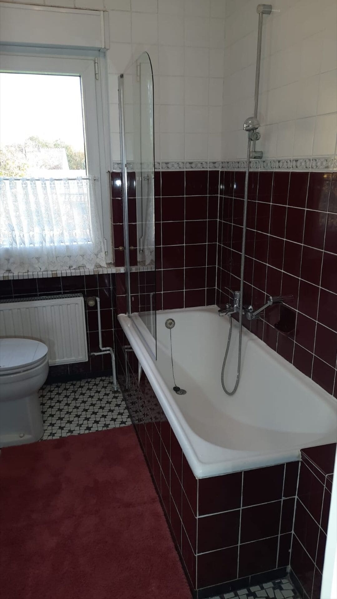 Une salle de bain avec une baignoire, des toilettes et une fenêtre avec un rideau.
