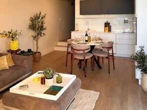 A modern living room with a dining area, a kitchen, and a sofa.