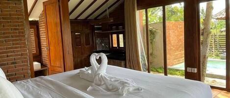 A spacious bedroom with a large bed, wooden beams, and a brick wall.