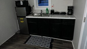 Une cuisine compacte équipée d’un réfrigérateur, d’un four à micro-ondes, d’un évier et d’une machine à café.