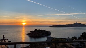 Un capvespre sobre una població costanera amb un turó destacat al fons.