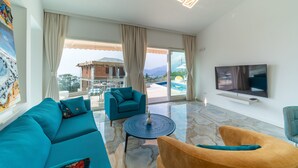 Un saló modern amb un sofà color turquesa, una taula de centre rodona i un televisor de pantalla plana fixat a la paret.