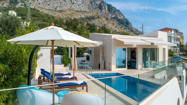 Zona de piscina moderna amb gandules i una piscina sense arestes de vidre que domina un paisatge montanyós.