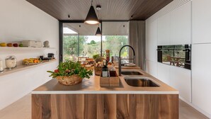 Eine moderne Küche mit einer Holztheke, einer Edelstahlspüle und Blick ins Freie.