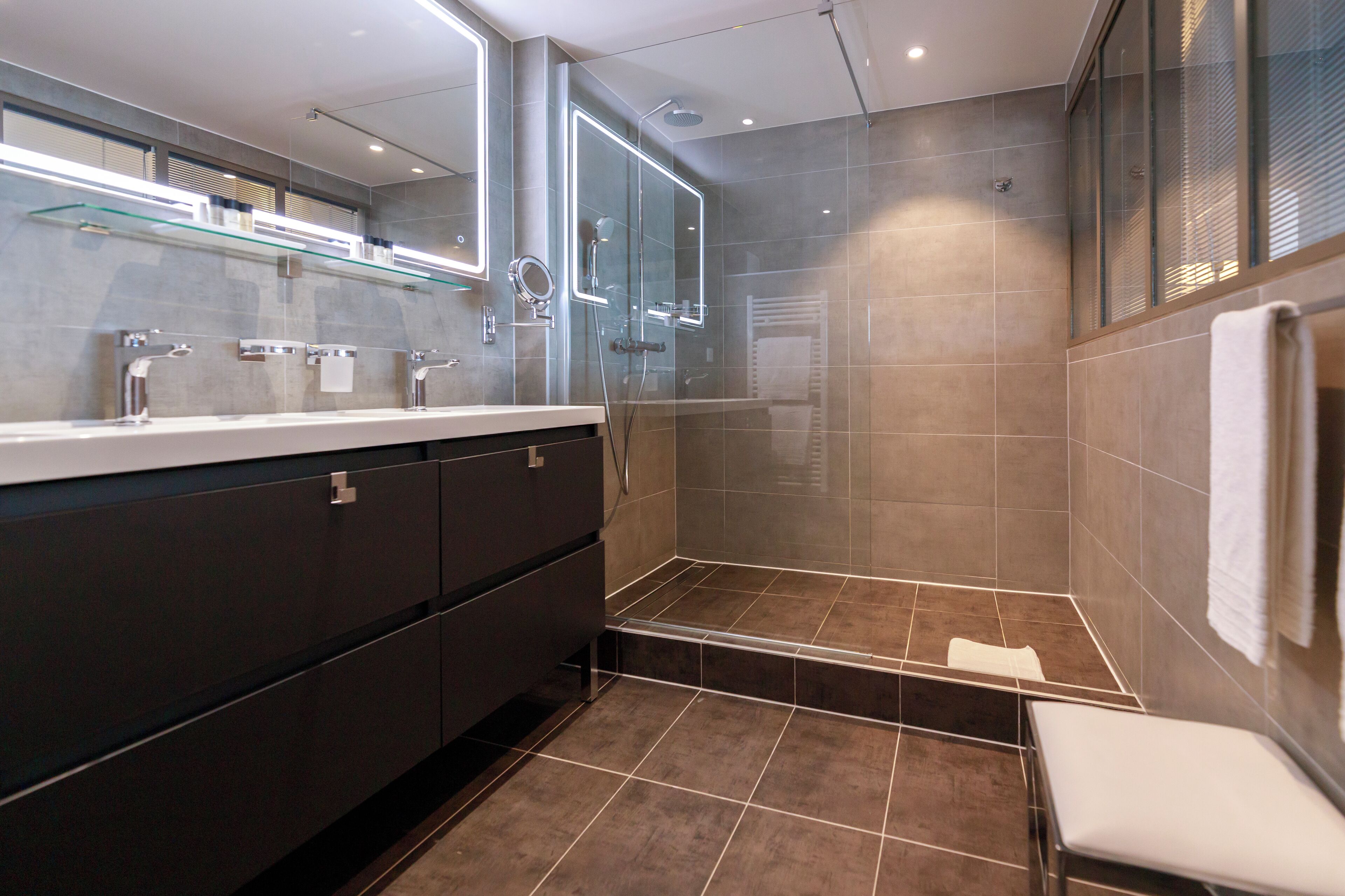 A modern bathroom with a glass-enclosed shower, a vanity with a mirror, and a towel rack.