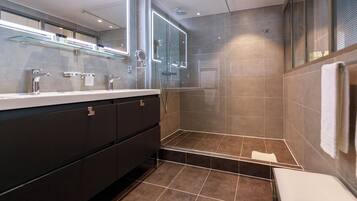 A modern bathroom with a glass-enclosed shower, a vanity with a mirror, and a towel rack.
