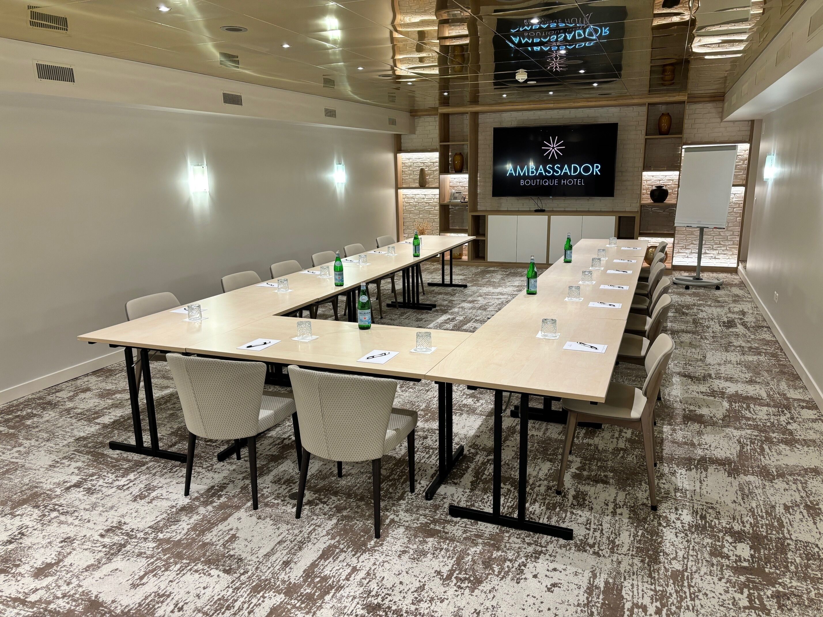Ett konferensrum med ett långt bord, stolar och en skärm som visar hotellets namn.